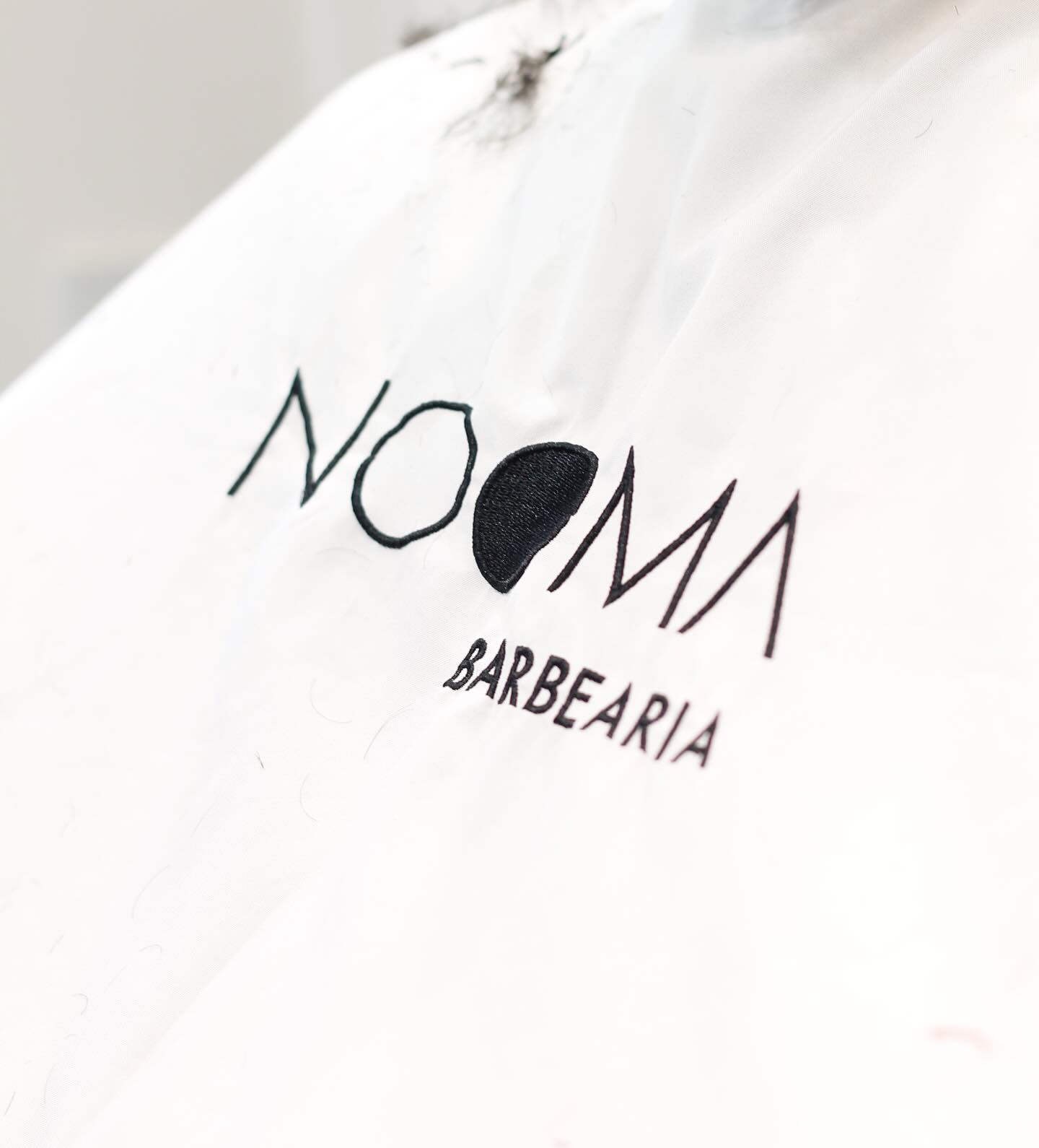 Capa NOOMA com logotipo bordado — detalhe do ofício